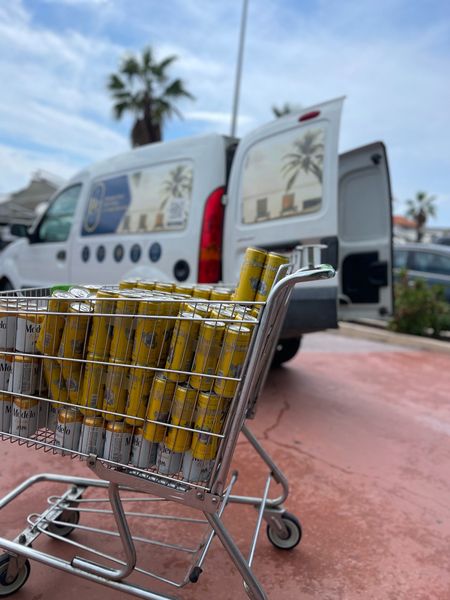 Shopping cart full of Modelo beer cans beside a delivery van