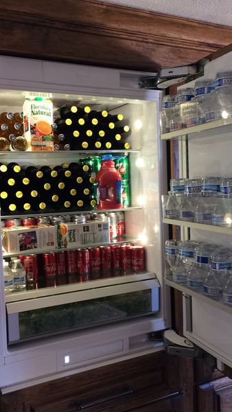 Beverage fridge stocked with bottled beer, cans of soda, bottled water and juice