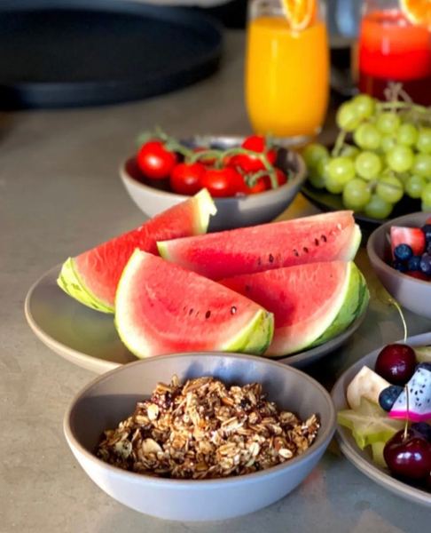 Watermelon slices, cherry tomatoes, green grapes, granola and fresh orange juice